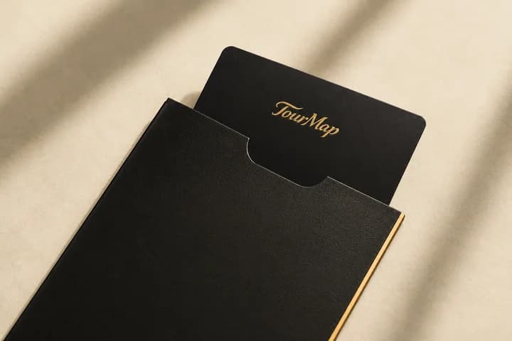 A black TourMap membership folder with the wordmark stamped in gold foil